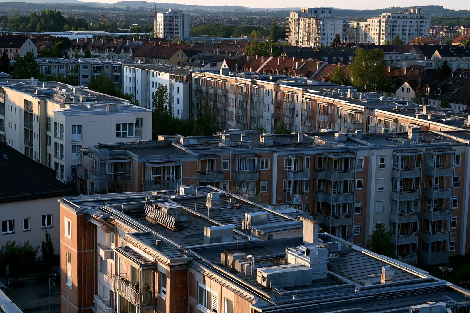 Vācijas pilsētas dzīvojamo māju jumti un apkures ventilācijas atveres siltā pēcpusdienas gaismā.